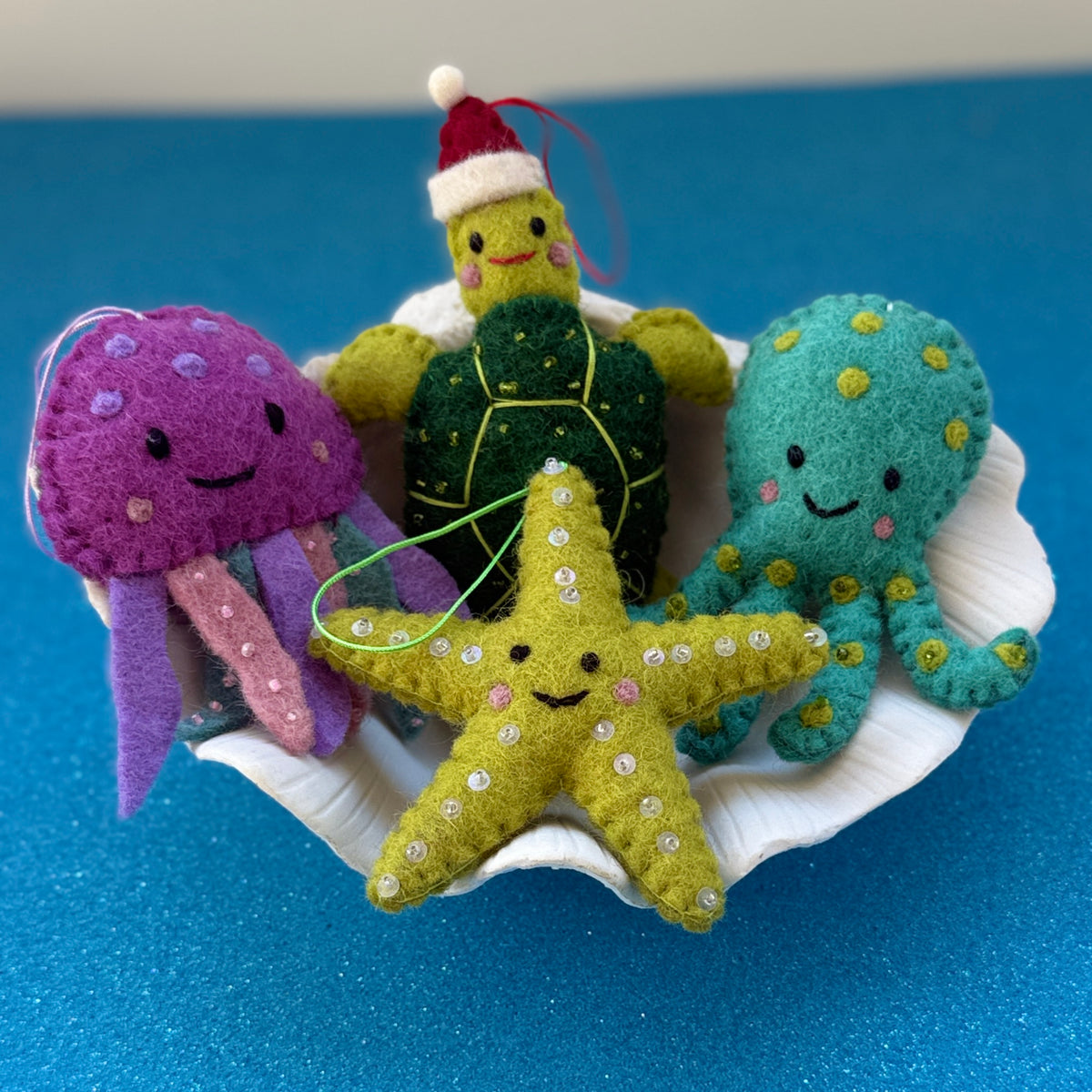 Colorful Starfish Christmas Decorations featuring starfish, turtle, jellyfish, and octopus in a shell against a blue background.