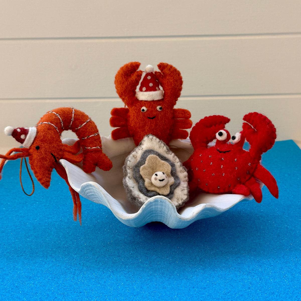Christmas prawns and lobster decorations displayed in a seashell with festive designs.