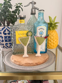 Christmas Margarita Decoration featuring two festive cocktails on a stylish bar cart with liquor bottles.