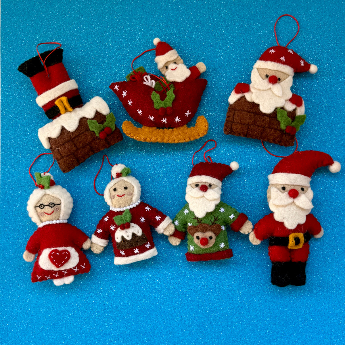 Colorful handmade felt Santa in sleigh Christmas decoration and festive characters on blue background.