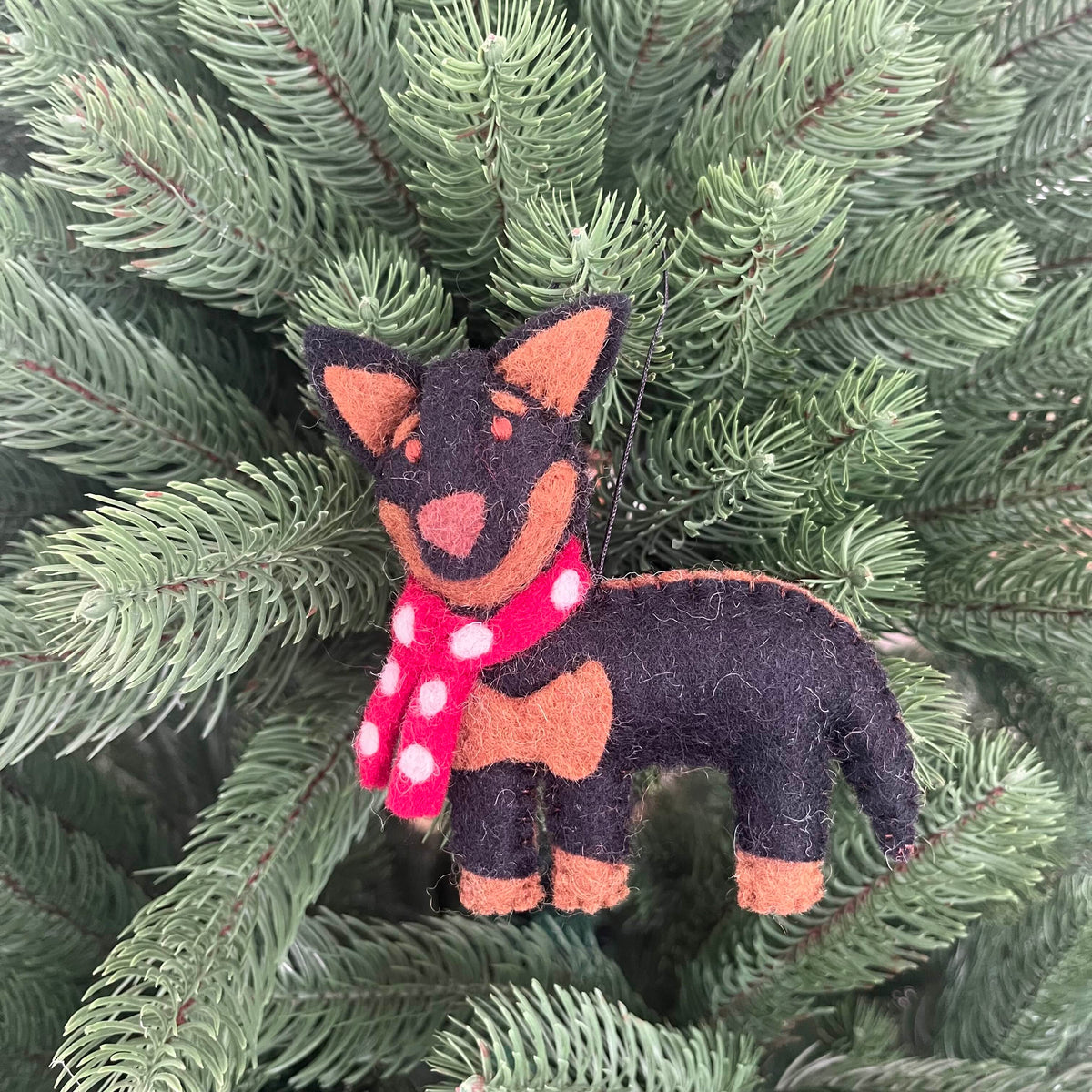 Kelpie dog Christmas decoration with a scarf hanging on a pine tree.