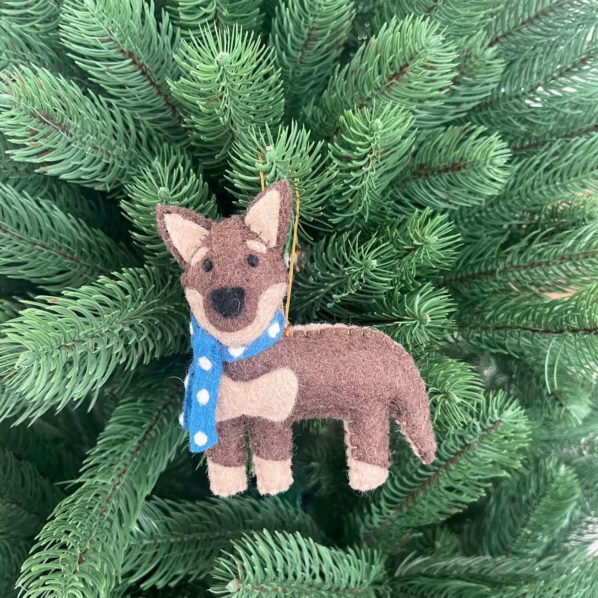 Kelpie dog Christmas decoration with a blue scarf hanging on a Christmas tree branch.