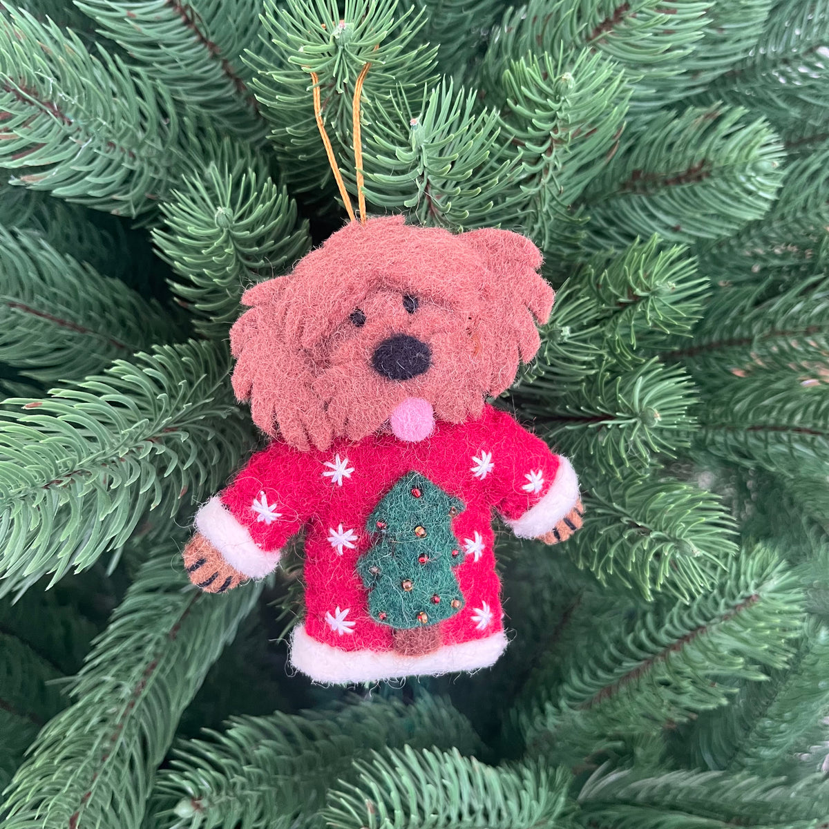 Dogs in Christmas sweater decorations hanging on a Christmas tree, showcasing a cute dog ornament in a festive sweater.