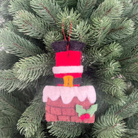 Santa stuck in chimney Christmas decoration hanging on a pine tree branch, featuring felt Santa and chimney design.