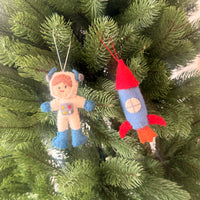 Christmas Astronaut & Rocket Decoration hanging on a Christmas tree, festive holiday ornaments.