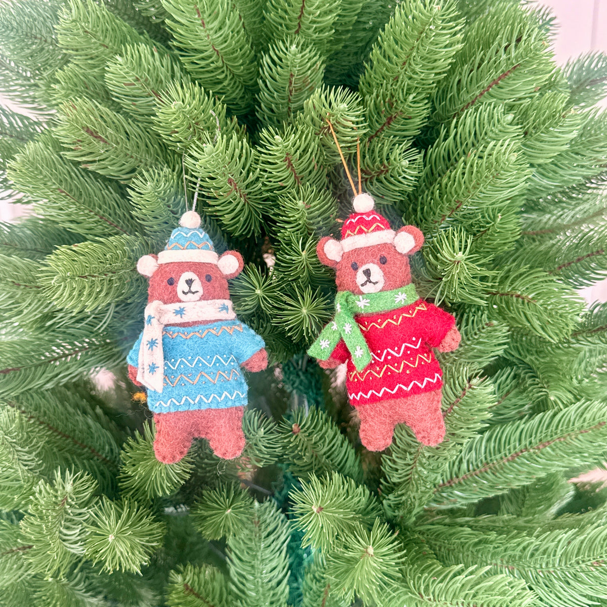 Bears in Christmas sweaters decorations in red and blue hanging on a Christmas tree, made from 100% New Zealand wool.