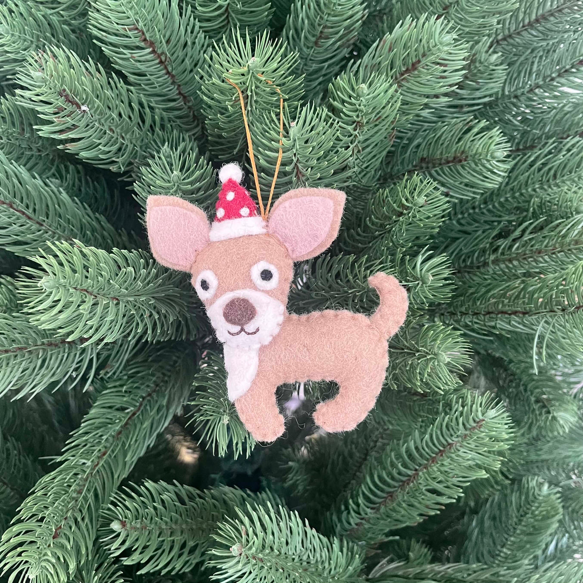 Chihuahua Christmas decoration featuring a cute felt Chihuahua ornament wearing a Santa hat, hanging on a Christmas tree.