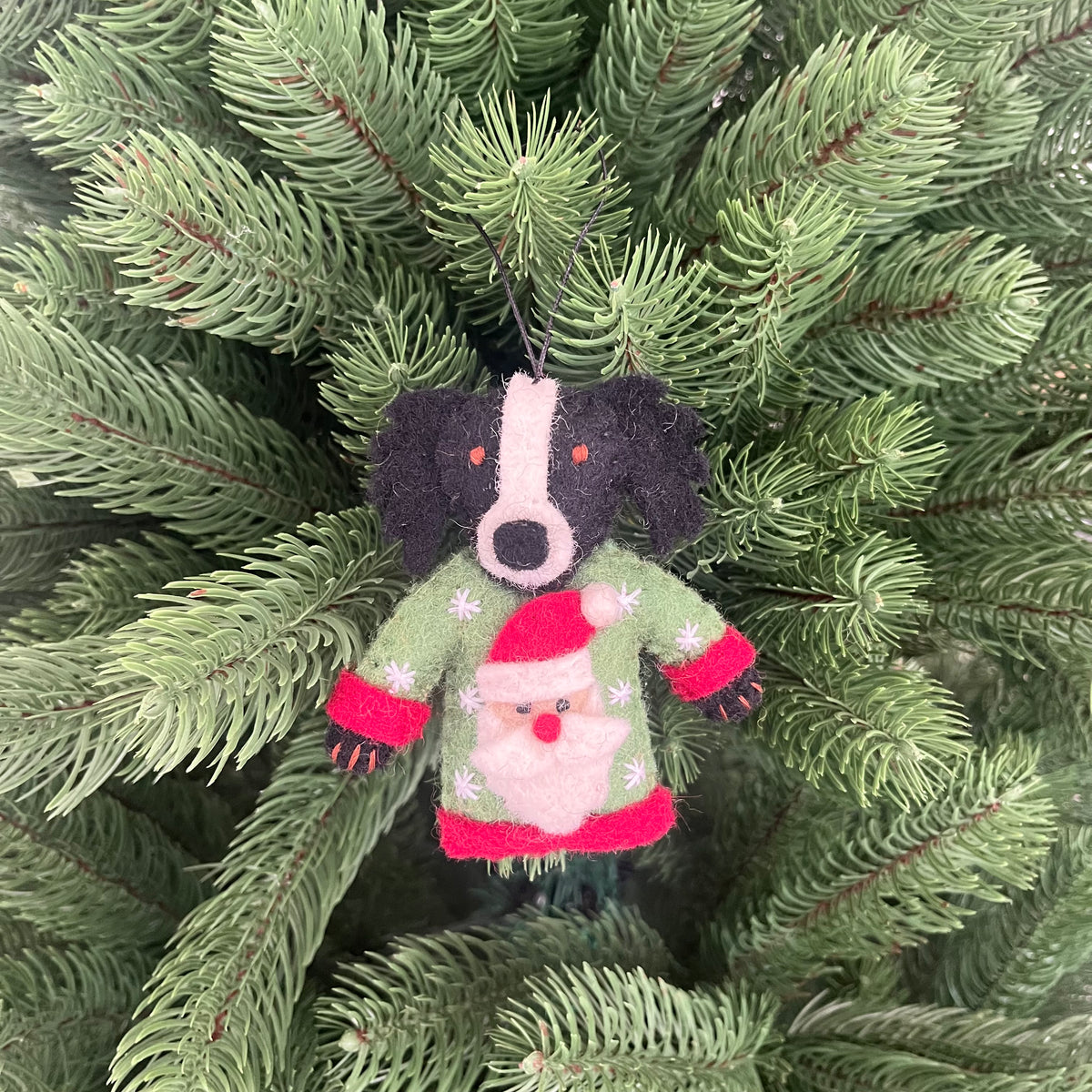 Dogs in Christmas sweater decorations hanging ornament on a Christmas tree.
