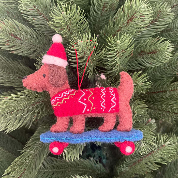 Christmas Dachshund on skateboard ornament wearing a red sweater and Santa hat, hanging on a Christmas tree.
