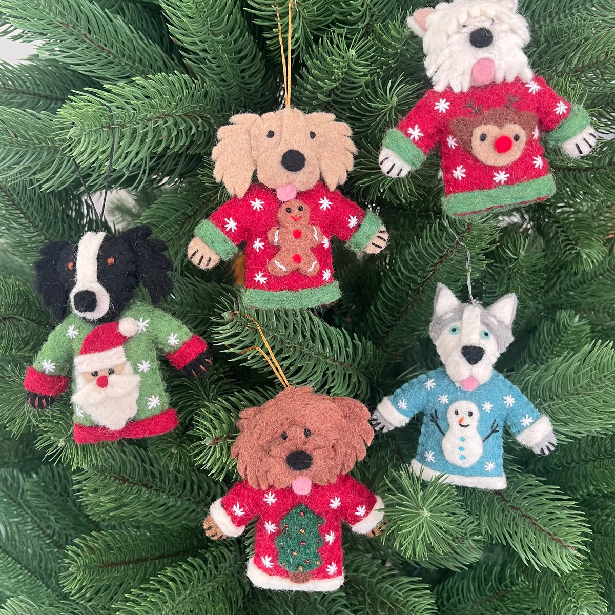 Dogs in Christmas sweater decorations hanging on a Christmas tree, featuring cute dog ornaments in festive sweaters.