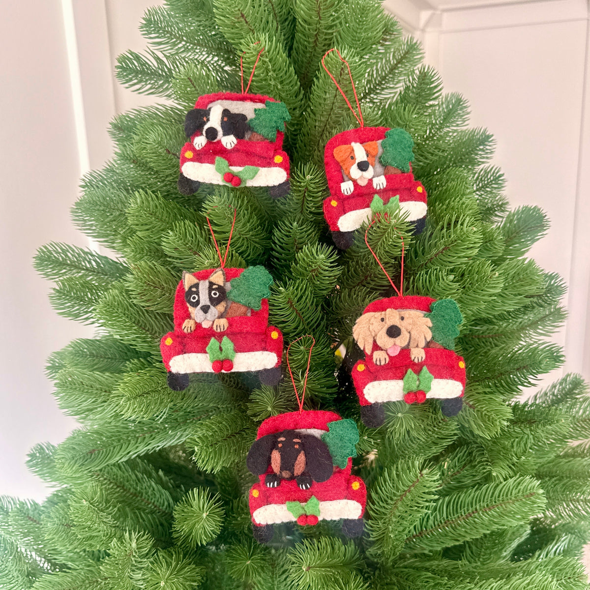 Christmas Collie in truck decorations hanging on a festive Christmas tree, featuring five adorable dog ornaments.