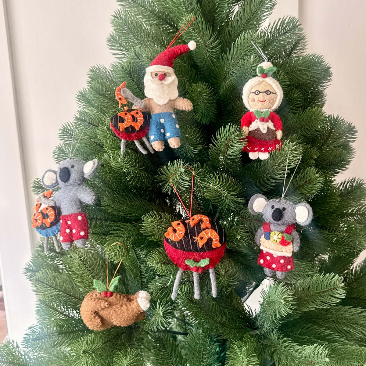 Santa and Mrs Claus with Christmas treats decorations featuring koalas and festive ornaments on a Christmas tree.