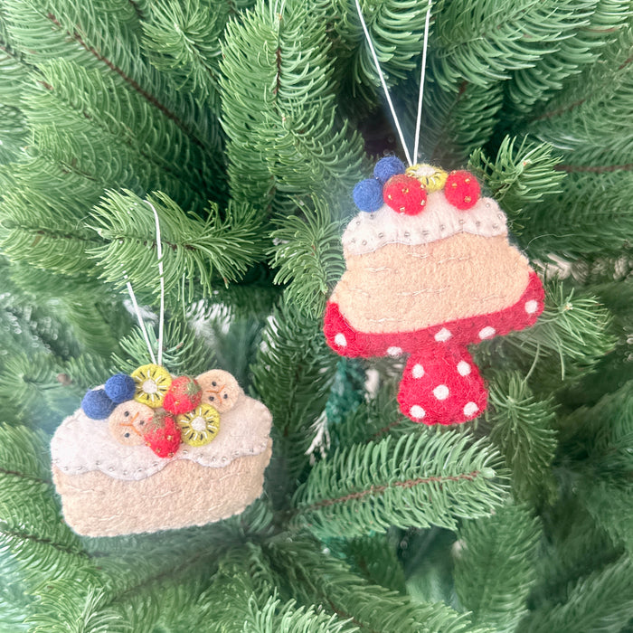 Handmade Christmas Pavlova decorations featuring felt cakes with vibrant toppings, hanging on a Christmas tree.