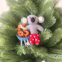koala with aussie christmas treats decorations wearing red shorts, holding a barbecue with prawns in a Christmas tree.