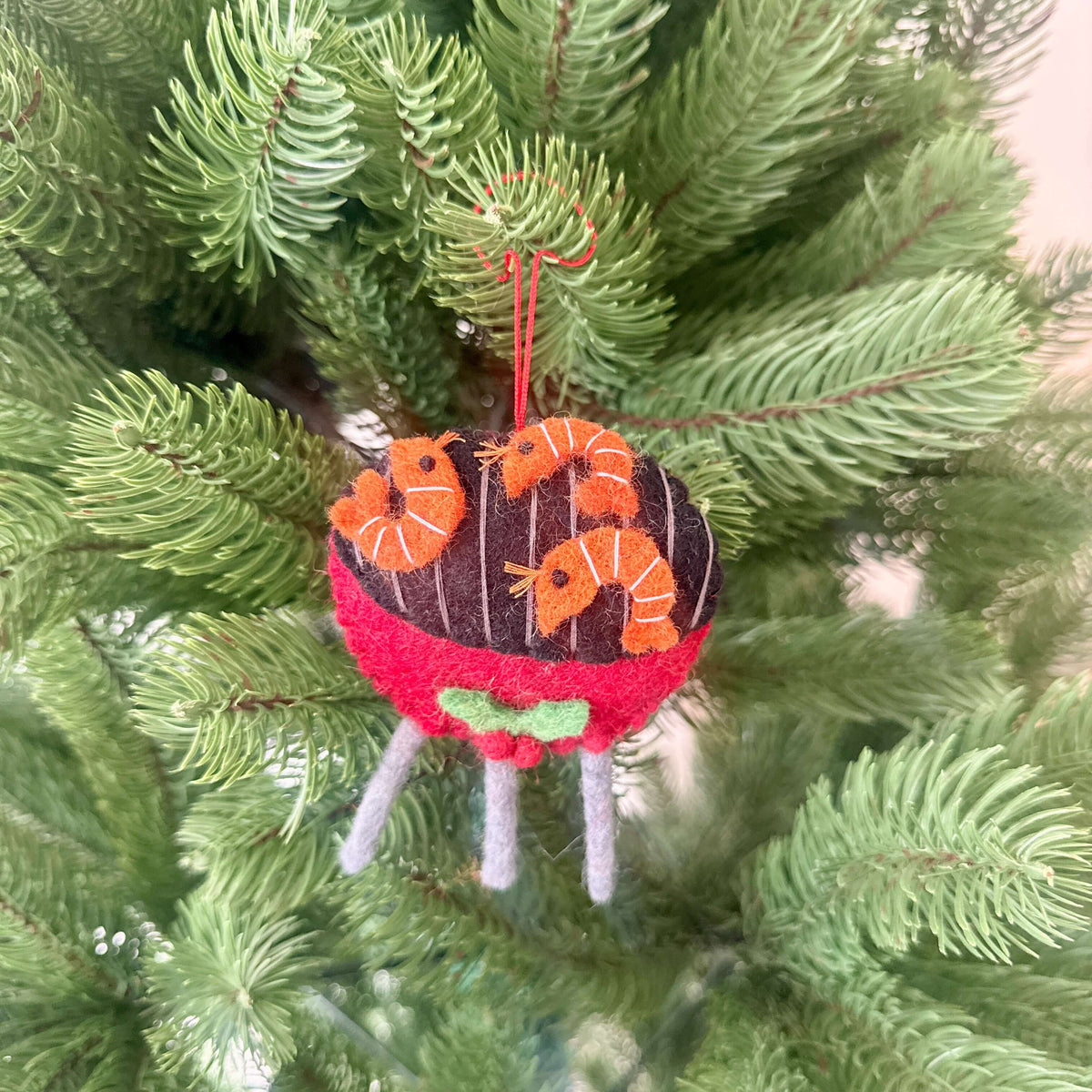 Prawn on BBQ Christmas decoration hanging on a Christmas tree, featuring felt shrimp and a vibrant barbecue design.