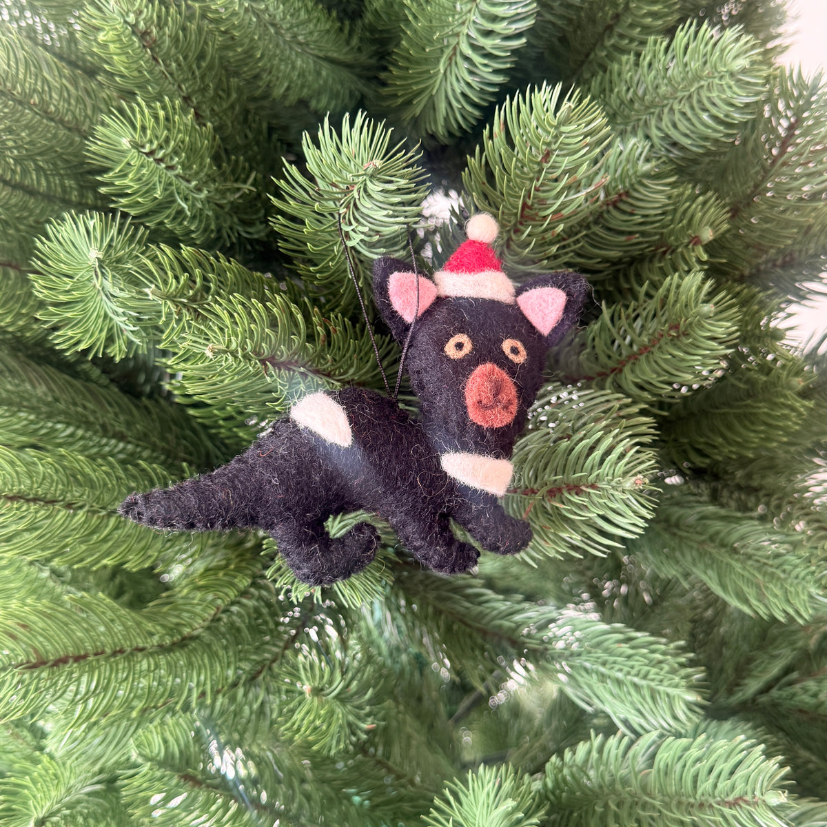 Tasmanian Devil Christmas Decoration hanging on a Christmas tree, featuring a playful design with a festive hat.