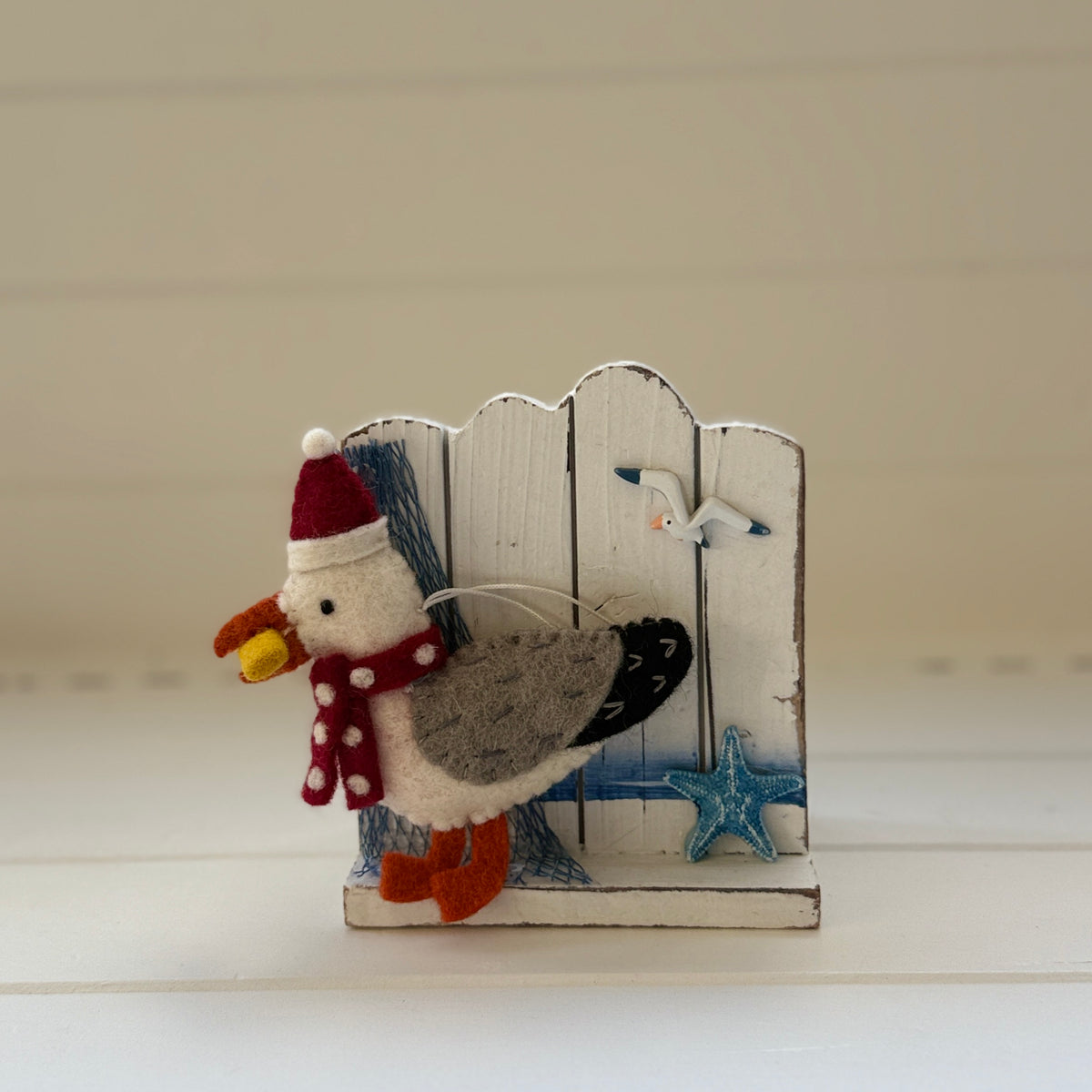 Christmas Seagull with chip decoration featuring a seagull in a Santa hat holding a chip next to a wooden fence.