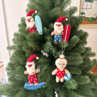 Surfing Santa Christmas Decoration featuring festive Santa and Mrs. Claus ornaments on a Christmas tree.