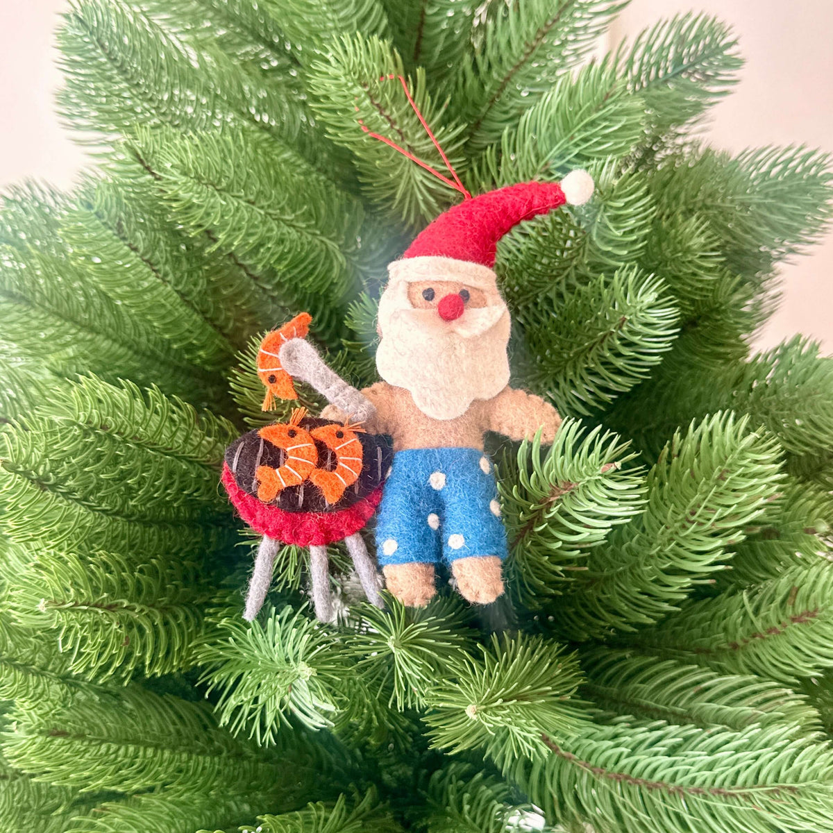 Santa and Mrs Claus with Christmas treats decorations featuring Santa in board shorts by a BBQ.