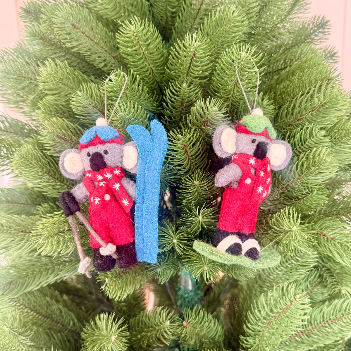 Christmas snowboarding & skiing Koalas hanging on a festive tree, showcasing adorable winter decorations.